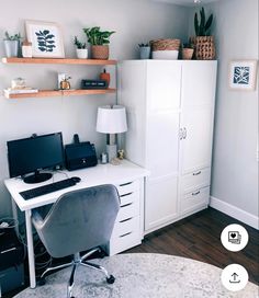 a desk with a computer on top of it next to a white cabinet and lamp