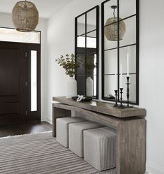 an entryway with mirrors, bench and stools on the carpeted floor in front of it