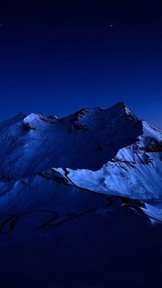 snow covered mountains at night with the moon in the sky