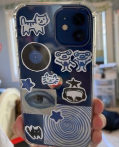 someone holding up their phone case with stickers on it