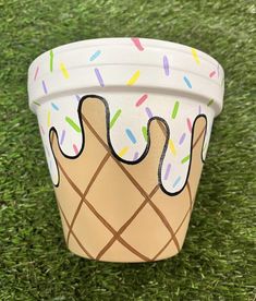 a paper cup with sprinkles and ice cream on it sitting in the grass