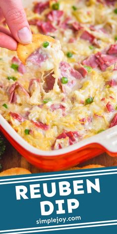 a hand dipping a tortilla chip into a casserole dish with ham and cheese