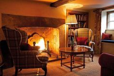 a living room filled with furniture and a fire place next to a window in front of a bookshelf