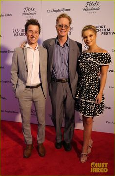 two men and a woman standing on a red carpet