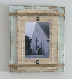 an old wooden frame with a cross hanging on the wall next to a white building