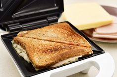 a toasted sandwich sitting on top of a black and white plate next to cheese