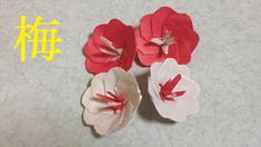 three red and white paper flowers with chinese characters in the background on a gray surface