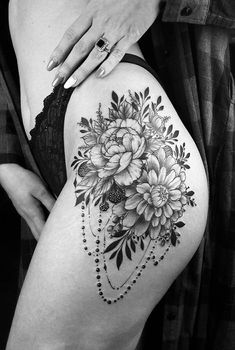 a black and white photo of a woman's thigh with flowers on the side