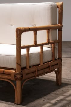 a couch made out of bamboo with white cushions