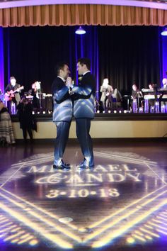 two men standing on top of a dance floor with their arms around each other in front of an audience