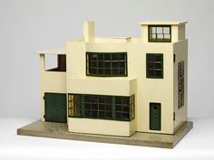 a white model house with green shutters and windows