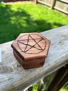 a wooden box with a pentagram on it sitting on a bench in the grass