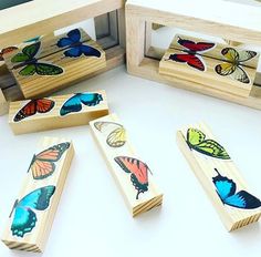 four wooden stamps with butterflies on them sitting in front of a box filled with other wood stamps