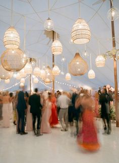 a group of people standing around each other under umbrellas with lights hanging from them