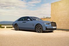 a blue rolls royce parked in front of a building