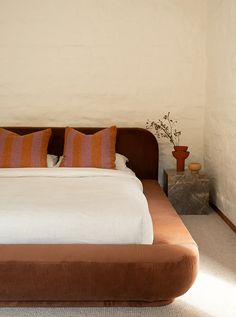 a large bed sitting in the middle of a bedroom next to a wall with two vases on it