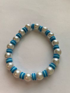 a blue and white beaded bracelet with pearls on it's end, sitting on a table