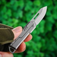 a person holding a knife in their hand with green leaves behind it and the background is blurry