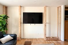 a flat screen tv mounted to the wall in a living room with wood framing around it