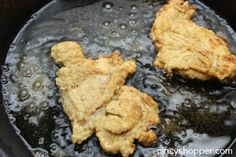 two pieces of chicken cooking in a skillet