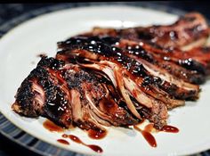 some meat is sitting on a plate covered in bbq sauce and drizzled with ketchup