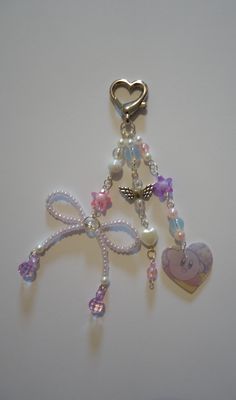 a key chain with charms attached to it on a white surface next to a heart