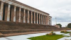 an old building with steps leading up to it and people walking on the other side