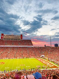 a football stadium filled with lots of people watching the sun go down on it's field