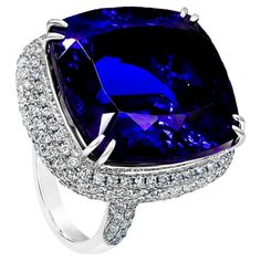 A splendid cocktail ring showcasing an amazing color-rich cushion cut tanzanite weighing 44.04 carats total. Elegantly set in a double claw prongs setting, with micro-pave diamonds set around the center stone. Diamonds weigh 2.43 carats total. Made in 18K White Gold. Size 6.75 US resizable upon request. Style available in different price ranges. prices are based on your selection. Please contact us for more information. Diamond Cocktail Ring, Tanzanite Diamond, Claw Prong, Custom House, Special Quotes, Diamond Cocktail Rings, Cushion Cut Diamonds, Micro Pave, Cocktail Ring