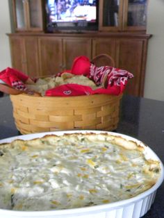 a casserole dish sitting on top of a table next to a basket filled with food