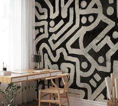 a desk and chair in front of a wall with black and white designs on it