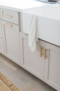 a white kitchen sink sitting next to a counter top with gold handles and knobs