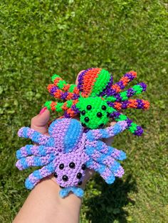 someone is holding some colorful crocheted items in their hand