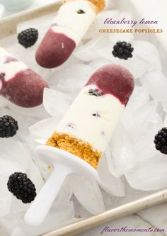 three popsicles with blackberries and raspberry toppings on top of ice