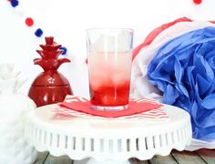 a red, white and blue drink sitting on top of a table next to a vase