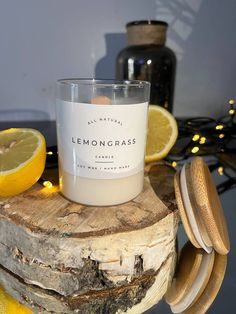 a candle sitting on top of a piece of wood next to lemons and a jar