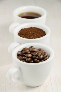 three cups filled with coffee beans next to each other