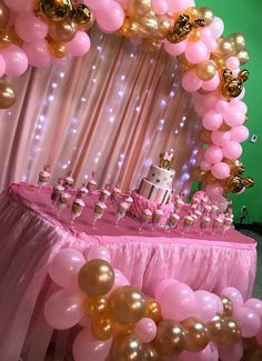 a table topped with lots of pink and gold balloons