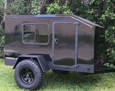 an off - road trailer is parked in the grass