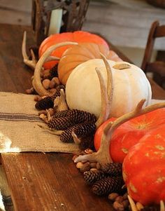 pumpkins and pine cones are arranged on a table