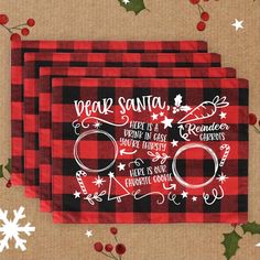 two red and black plaid christmas placemats with white lettering on them, surrounded by holly