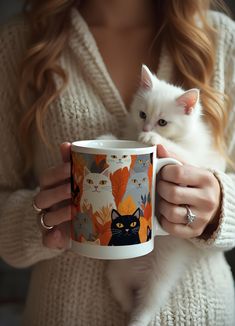 a woman holding a coffee mug with cats on it