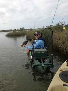 a man in a small boat with a fish net on the back of it and another person holding a dog