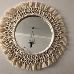 a round mirror hanging on the wall with tassels around it's edges