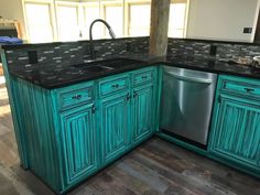 a kitchen with green cabinets and black counter tops