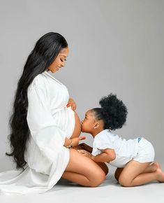 a pregnant woman and her child are sitting on the floor