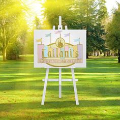 a white sign sitting on top of a lush green field next to trees and grass