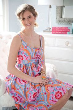 a woman is sitting on a white chair in a room with pink and blue decor