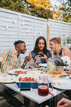 four people sitting around a table with food on it