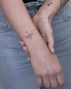 a woman with a small tattoo on her arm holding the wrist of another person's hand